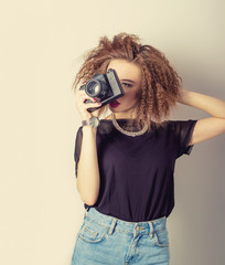 sexy woman in jeans with a camera in the hands of curly hair