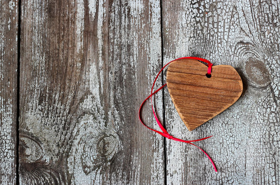 Decorative wooden heart with red ribbon on a wooden table