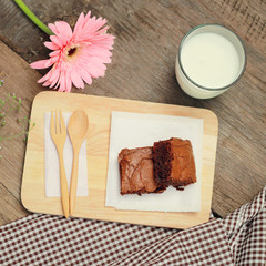Tasty brownies with glass of milk and flower, retro filter effec