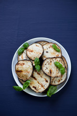 Grilled aubergine slices, dark blue wooden surface, above view