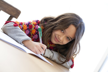 Niña con poncho de colores escribiendo