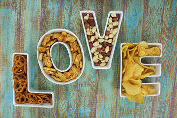 Snacks in Love shaped letter bowls on rustic background