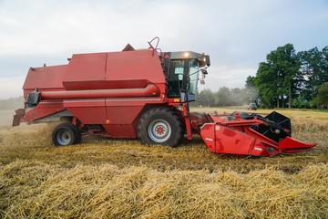 Obraz premium Roter Mähdrescher mit Beleuchtung bei der Getreideernte