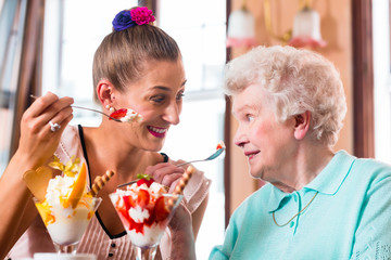 Oma und Enkelin essen Eisbecher im Cafe