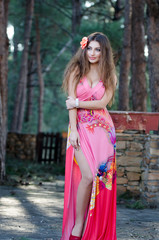 Lovely lady wearing elegant long dress standing among the trees