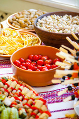 close up of a bowl of pistachio nuts, cheese, peanuts, cherry to