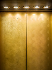 Gold metal door of elevator with spotlights