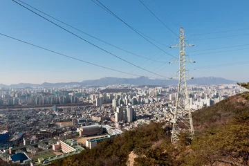 Fototapeten Power transmission line pole and wires on a hill over a city © fdsmsoft