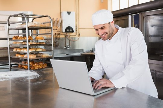 Smiling baker using laptop on worktop