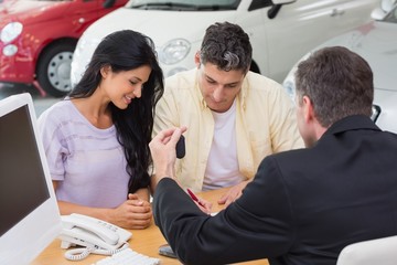 Smiling couple signing salesman contract