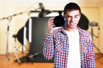 Handsome photographer with camera in photo studio