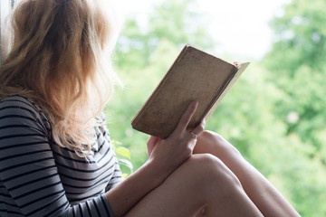 Woman lying in a garden and enjoying book reading