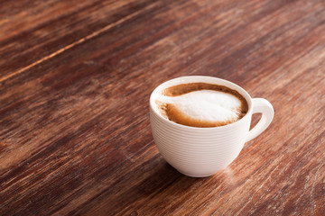 A cup of hot latte  coffee  on a wooden table.