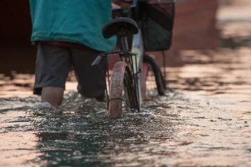 Foto op Aluminium Biker on a flooded road during a flood caused by heavy rain, Tha © wildarun