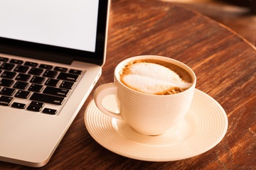 Hot latte coffee cup in a white cup on a table laptob in coffee