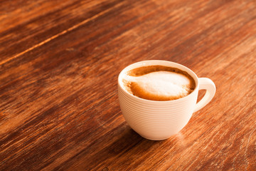 A cup of hot latte  coffee  on a wooden table.