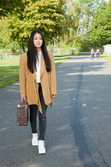 Young woman with suitcase running down the street