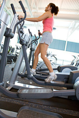 Fototapeta na wymiar Gym: Woman Doing Aerobic Exercise on Elliptical Machine