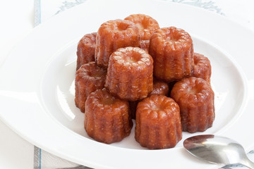 Canelés de Bordeaux empilés sur assiette blanche