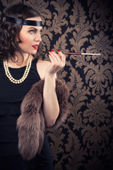 beautiful retro woman holding mouthpiece against vintage wallpap