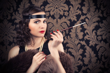 beautiful retro woman holding mouthpiece against vintage wallpap
