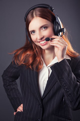 beautiful business woman with headphones against dark grey backg