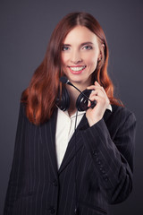 beautiful business woman with headphones against dark grey backg