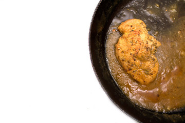 Fried chicken cutlet with sauce in skillet. Photo.