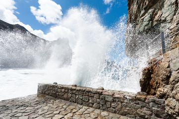 Welle bricht an Hafenmauer