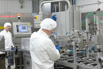 two  workers in uniforms at production line in plant