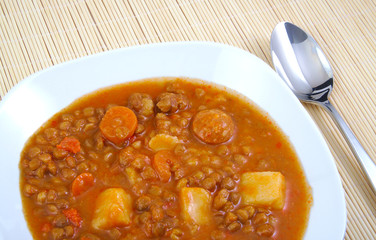 Brown cooked lentils with sausage, carrot and potato with metal