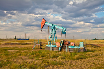 Fototapeta na wymiar Oil pump in the field on a background cloudy sky