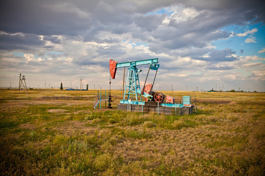 Oil pump in the field on a background cloudy sky
