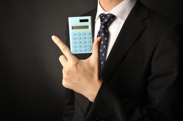 水色のデジタル計算機を手にしているスーツのビジネスマン男性