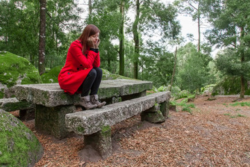 Naklejka na ściany i meble Young woman feeling depressed sitting on a stone table and bench