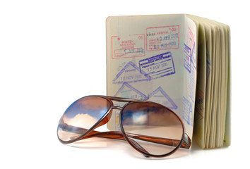 Journal, passport and sunglasses on white.