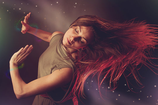 Beautiful woman dancer dancing over dark background with light r