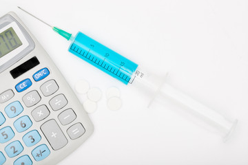 Calculator and a syringe with blue liquid inside