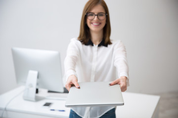 Happy businesswoman giving laptop on camera. Focus on laptop