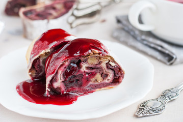 Cherry and walnut strudel on a white table. Closeup