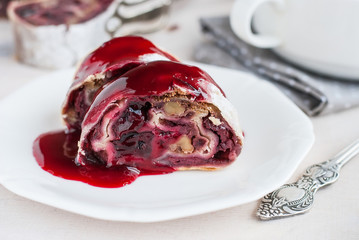 Cherry and walnut strudel on a white table. Closeup