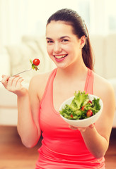 smiling teenage girl with green salad at home