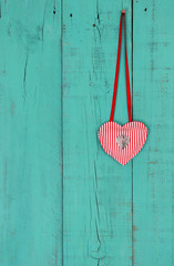 Heart and lock hanging by ribbon on wood background