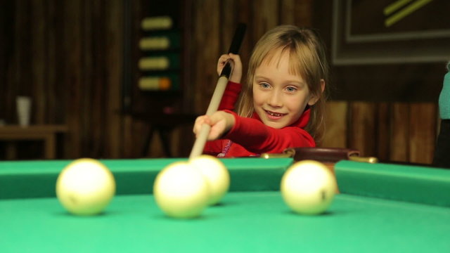 Little girl plays billiards