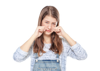 Crying young teenage girl in jeans overalls isolated