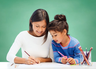 happy teacher and little school girl drawing
