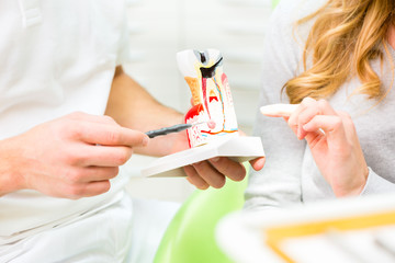 Zahnarzt erklärt Patientin Behandlung