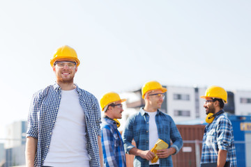 group of smiling builders in hardhats outdoors