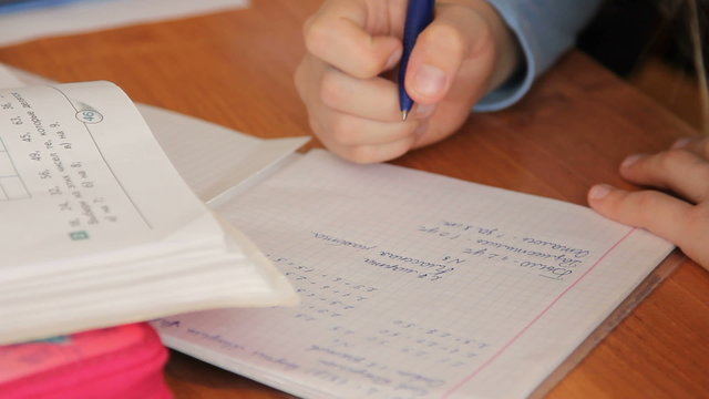 Pupil at the school writes in a notebook, performs tasks