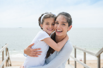 beautiful mom and her daugther at seaside smiling at camera